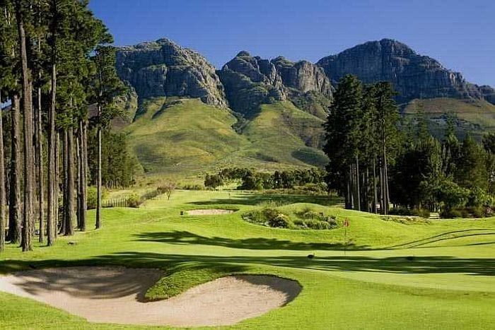 A golf course with mountains in the background and trees in the foreground