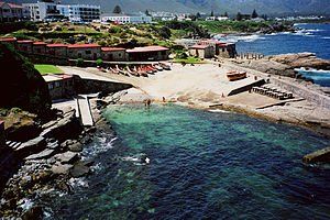 An aerial view of a beach and a body of water with buildings in the background.