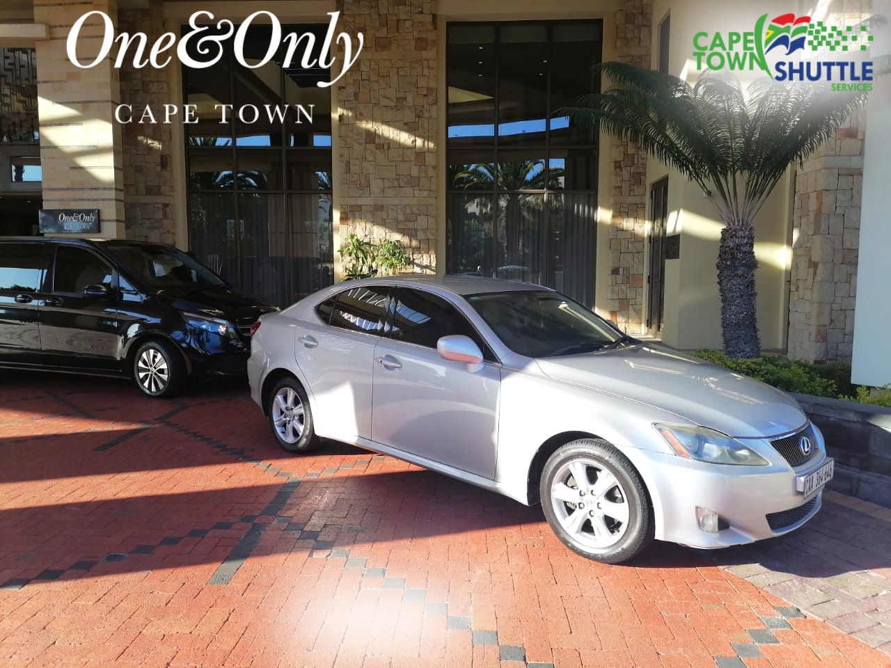 A silver car is parked in front of a building.