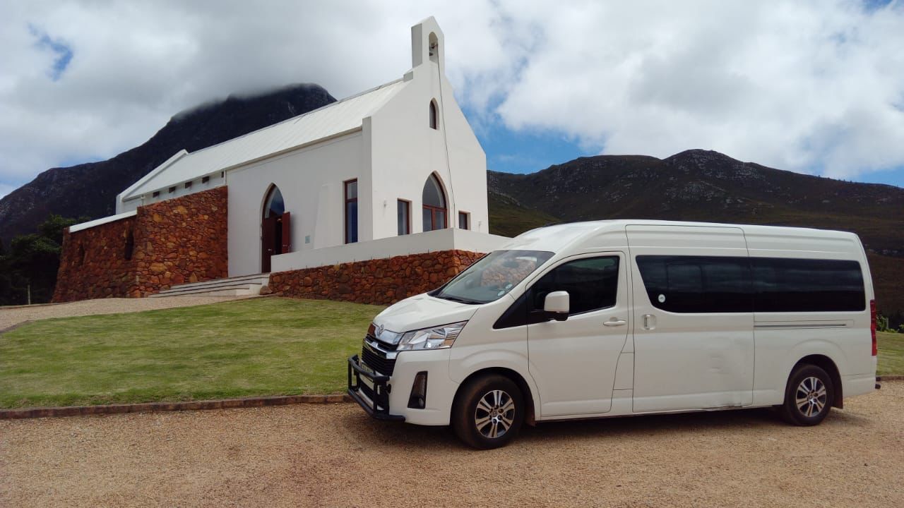 A white van is parked in front of a white church.