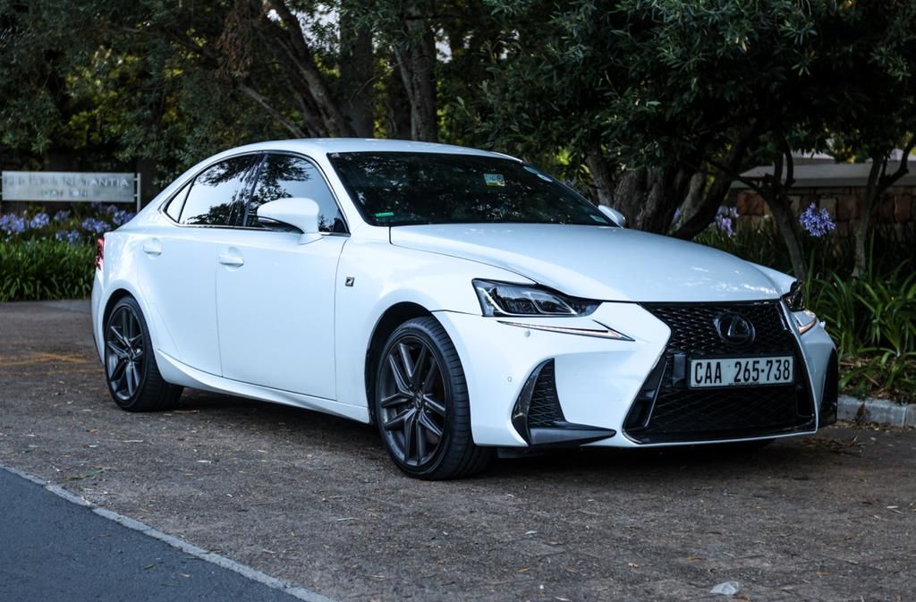 A white lexus is parked on the side of the road.