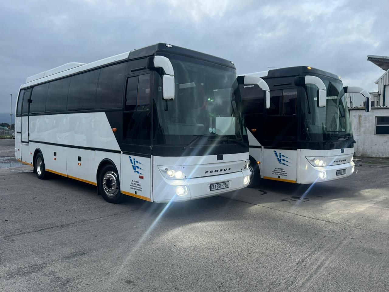Two buses are parked next to each other in a parking lot.