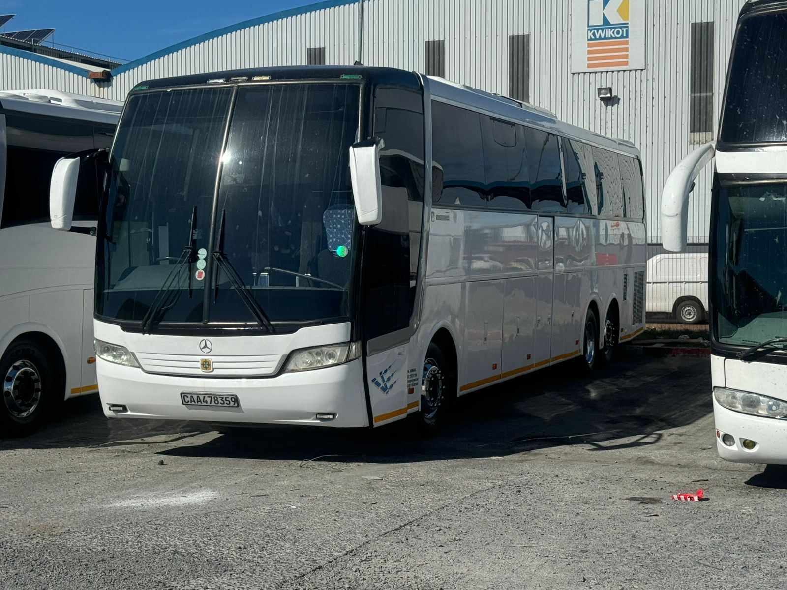 Several buses are parked in front of a building with the letter k on it