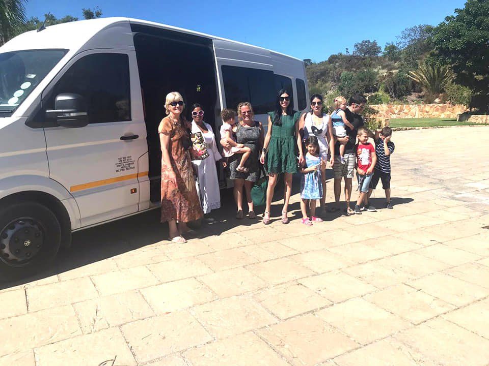 A group of people are standing in front of a white van.
