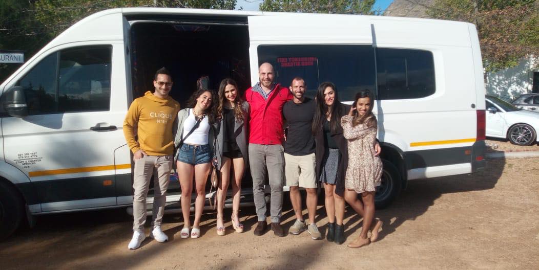 A group of people are posing for a picture in front of a white van.