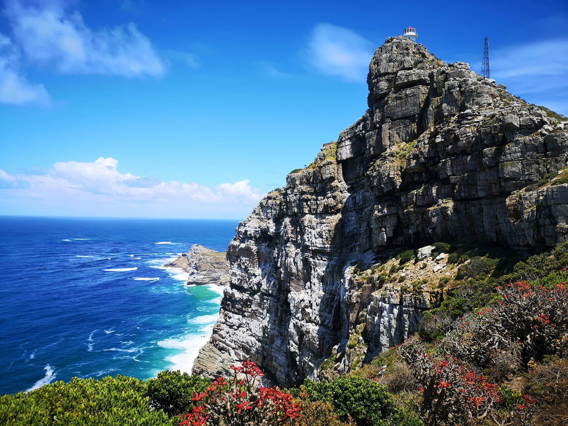 A cliff overlooking the ocean with a lighthouse on top of it.