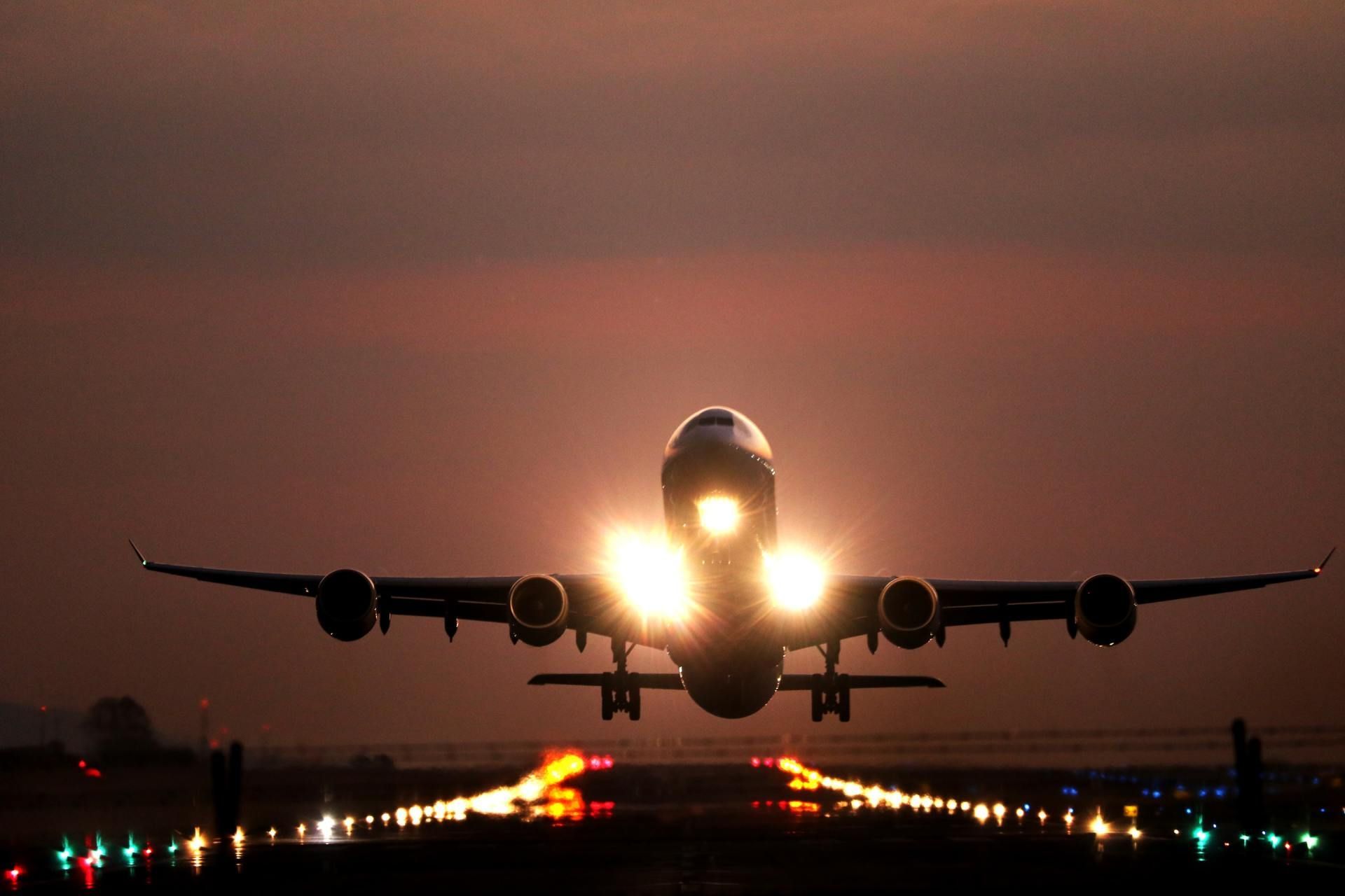 A large passenger jet is taking off from an airport runway at night.