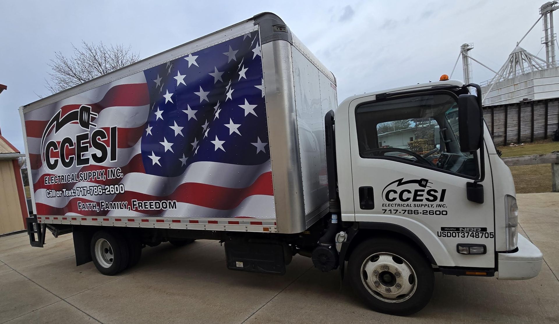 White CCEI truck with US flag wrap on side, parked.