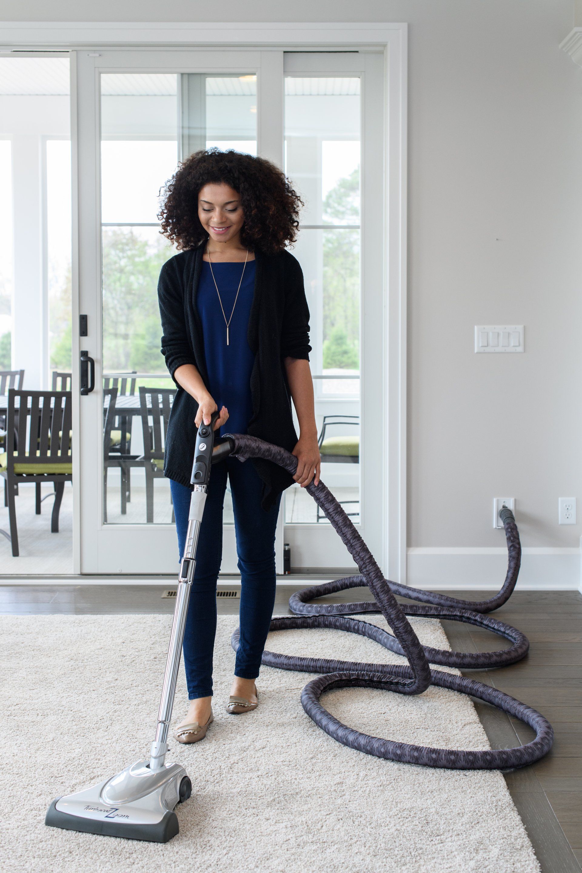 A woman is using a vacuum cleaner to clean a carpet in a living room.