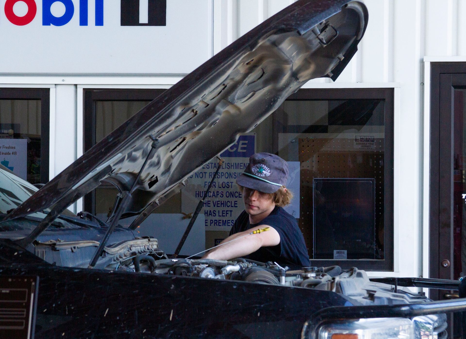 A person is holding a air filter in front of a car engine.