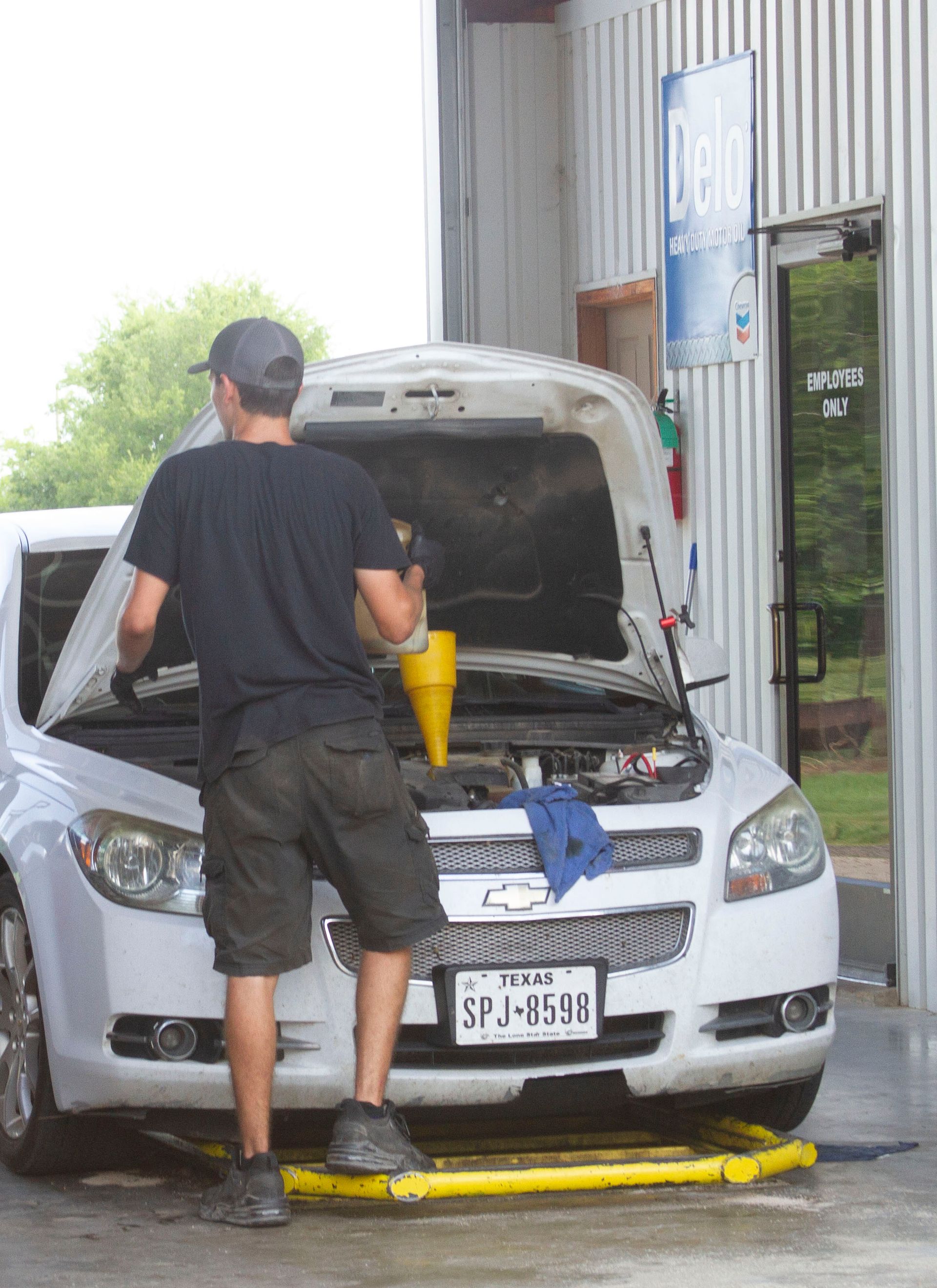A man is pouring oil into a car engine.