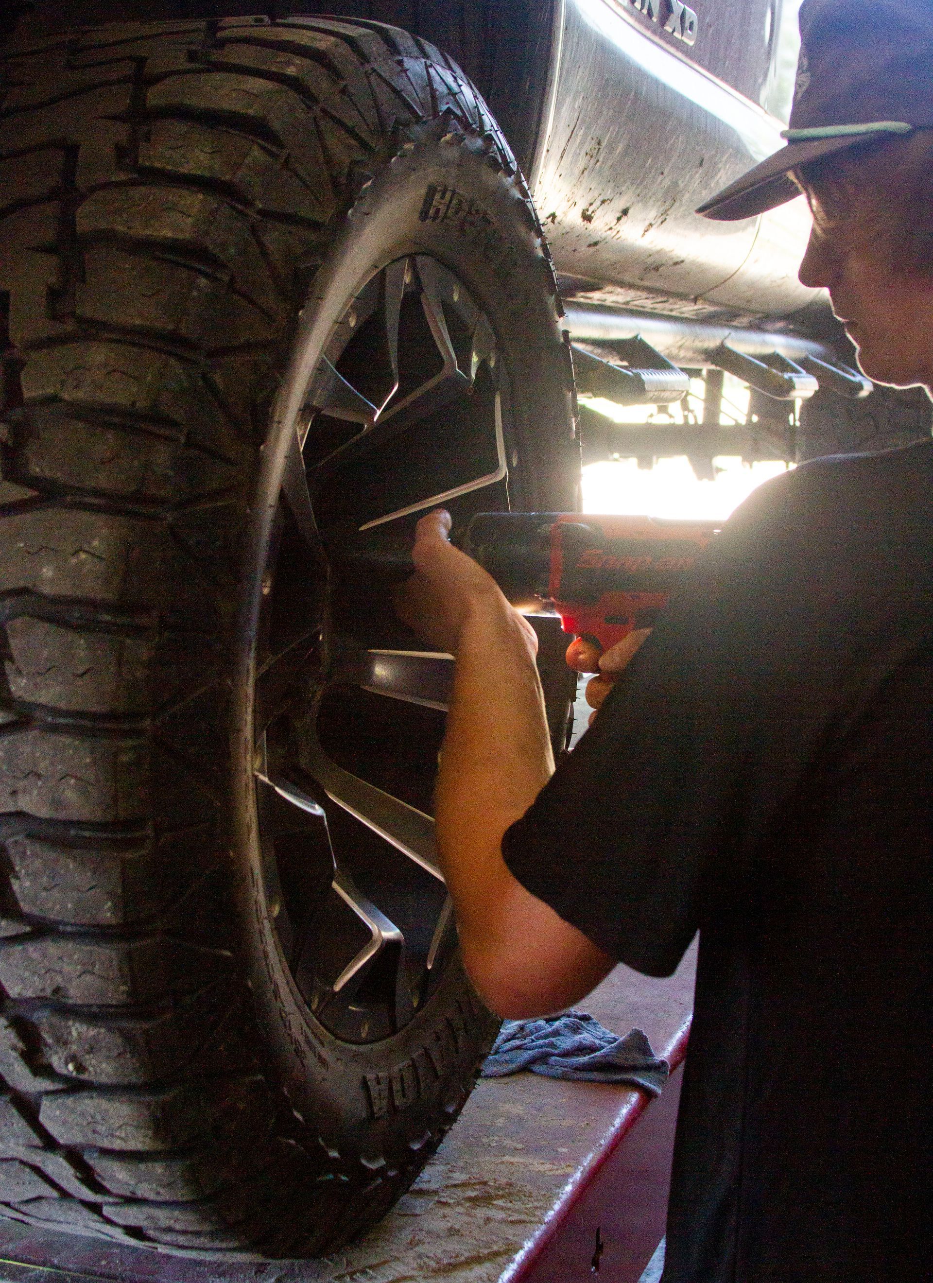 A man is changing a tire on a car in a garage.