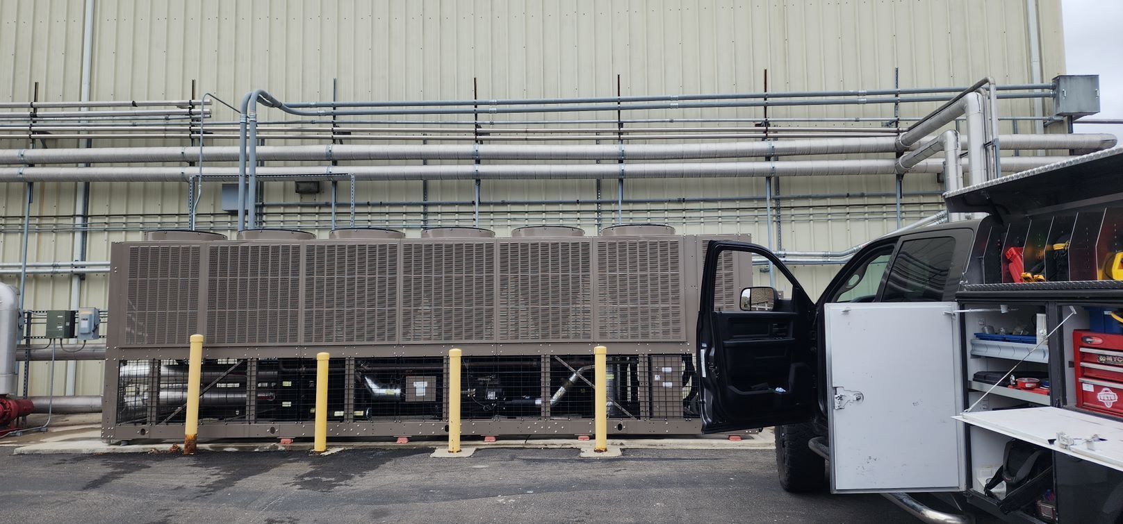 A truck is parked in front of a building with pipes.