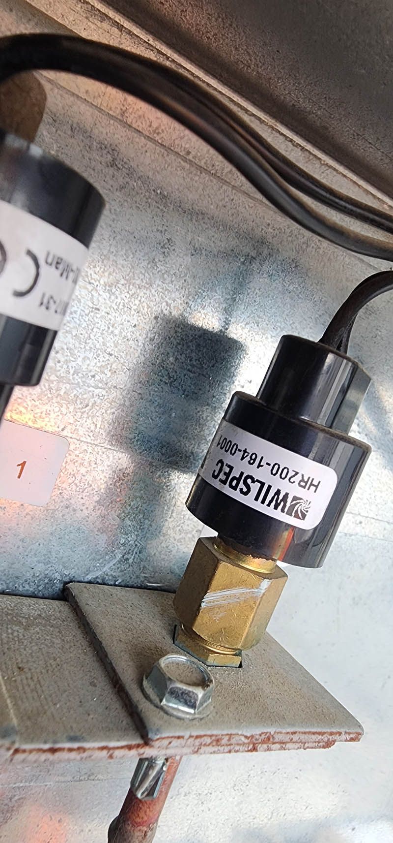 A close up of a pressure switch on a metal surface.