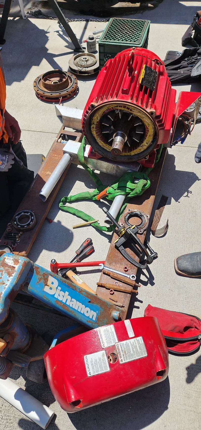 A red motor is sitting on top of a wooden table surrounded by tools.