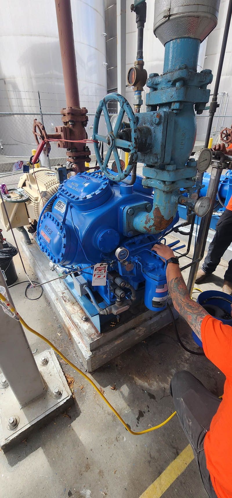 A man is working on a large blue machine in a factory.
