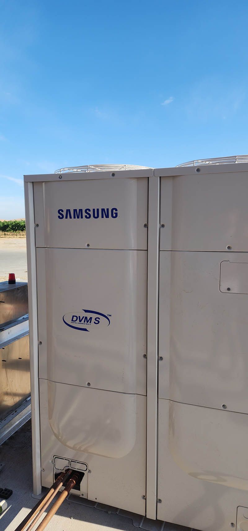 A samsung air conditioner is sitting on top of a building.
