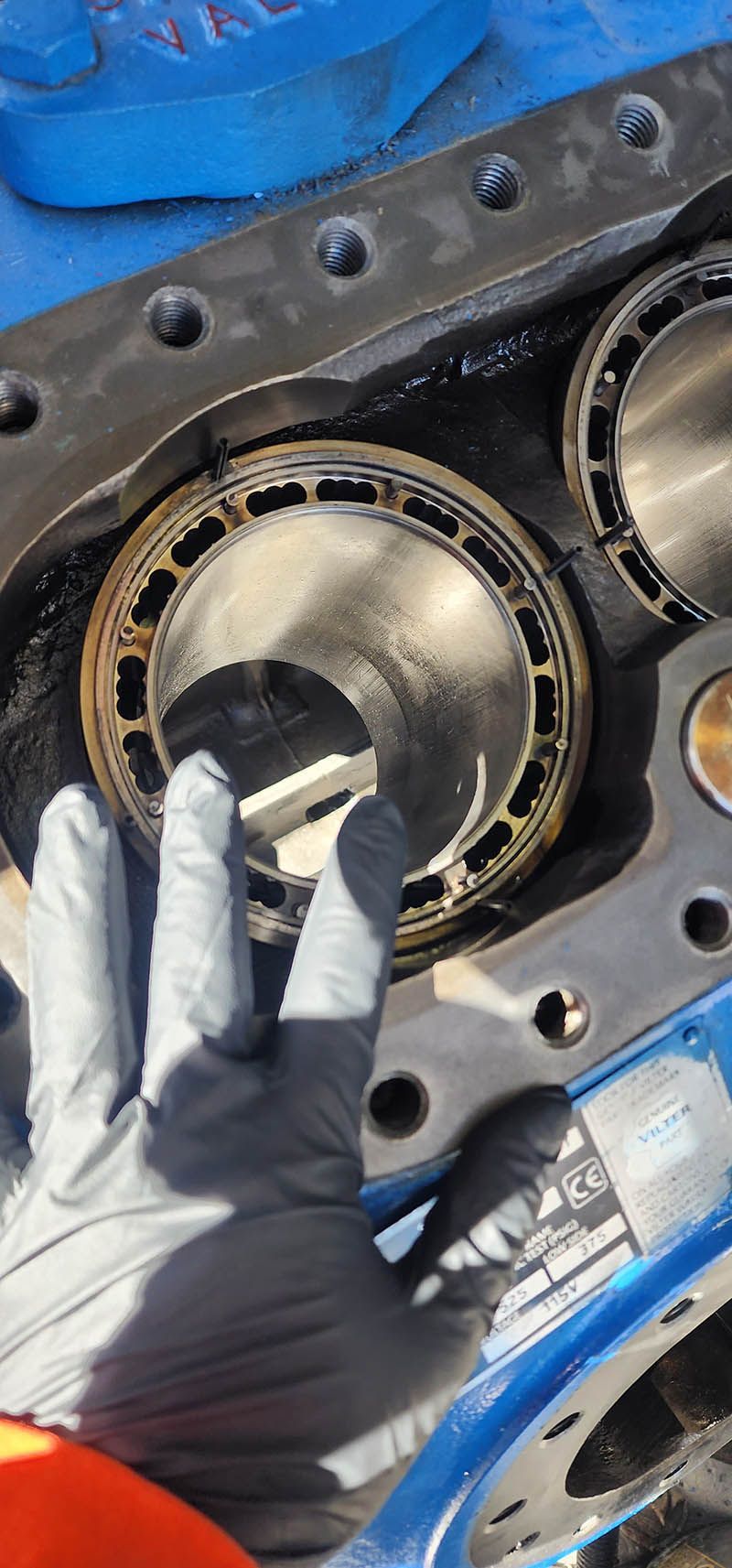 A person wearing gloves is holding a piece of metal in their hand.