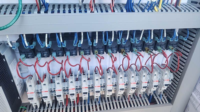 A bunch of electrical wires are hanging from a ceiling.