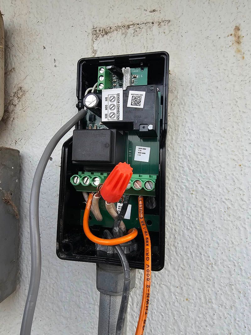 A black box with wires coming out of it is attached to a wall.