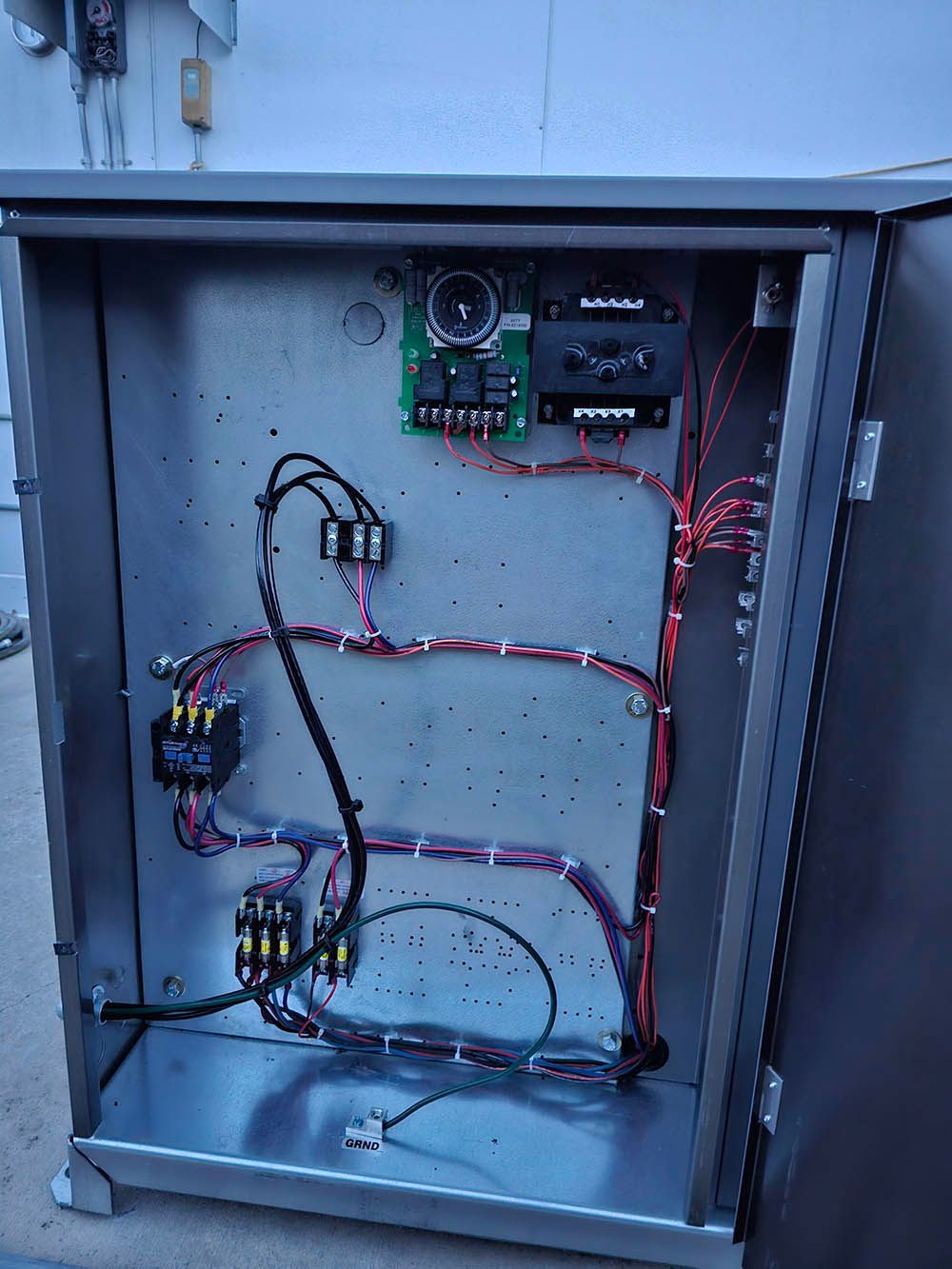 The inside of a metal box with wires coming out of it.