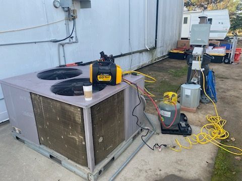 A large air conditioner is being serviced outside of a building.
