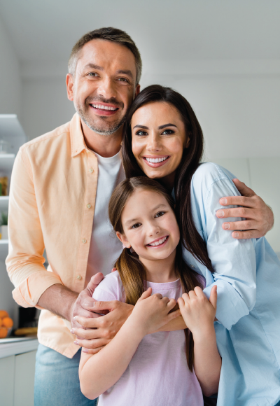 Smiling family of three hugging together in a bright kitchen