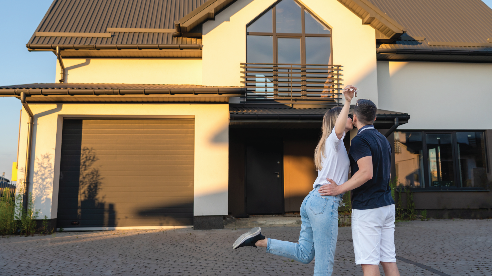 Couple embracing in front of a modern house at sunset