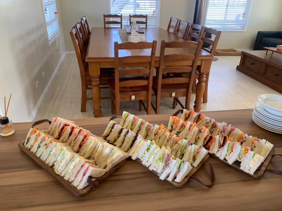 Trays of Sandwiches Are Sitting on A Wooden Table — Every Occasion Catering in Tamworth, NSW