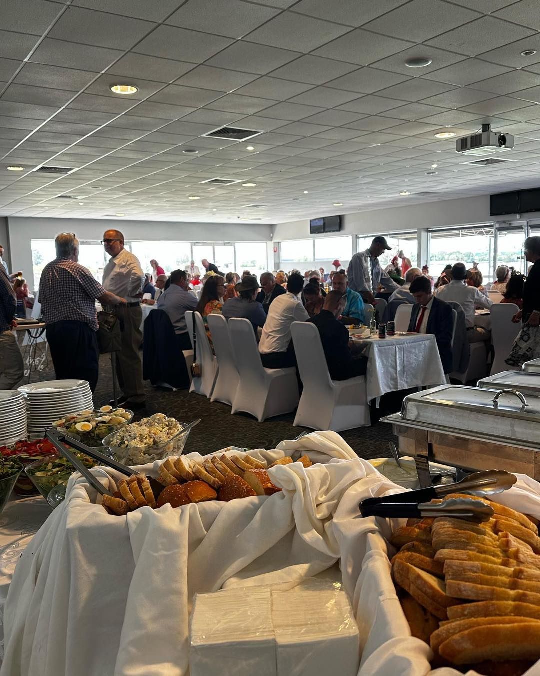 A Large Room Filled with People Sitting at Tables and A Buffet Table — Every Occasion Catering in Currabubula, NSW