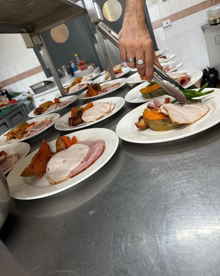 A Person Is Cutting a Piece of Meat on A Plate in A Kitchen — Every Occasion Catering in Gunnedah, NSW