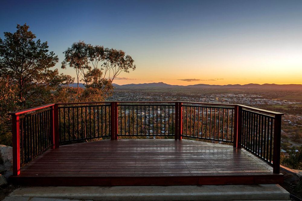 A Wooden Deck With A Railing Overlooking a City at Sunset — Every Occasion Catering in Tamworth, NSW