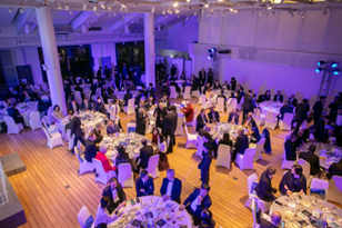 正式活動在一個大房間舉行，有圓桌、客人，還有白色和紫色的燈光。