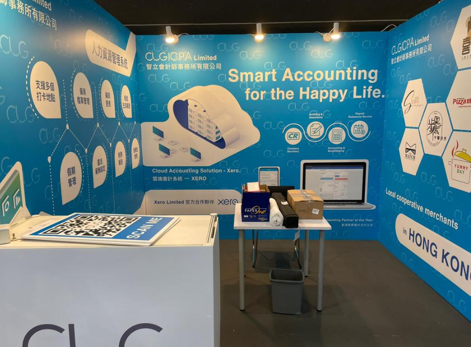 A trade show booth with blue branding, a computer, and product displays. The theme is 