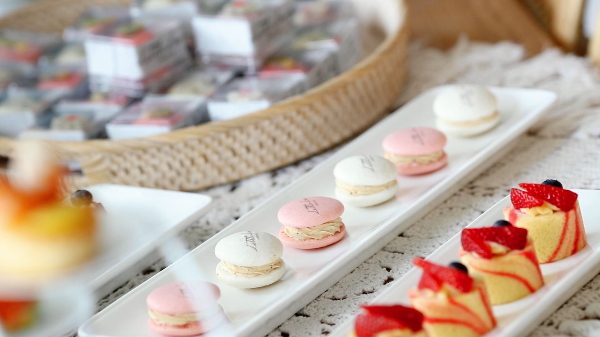 A tray of assorted desserts including macarons and small cakes, arranged on a table setting.