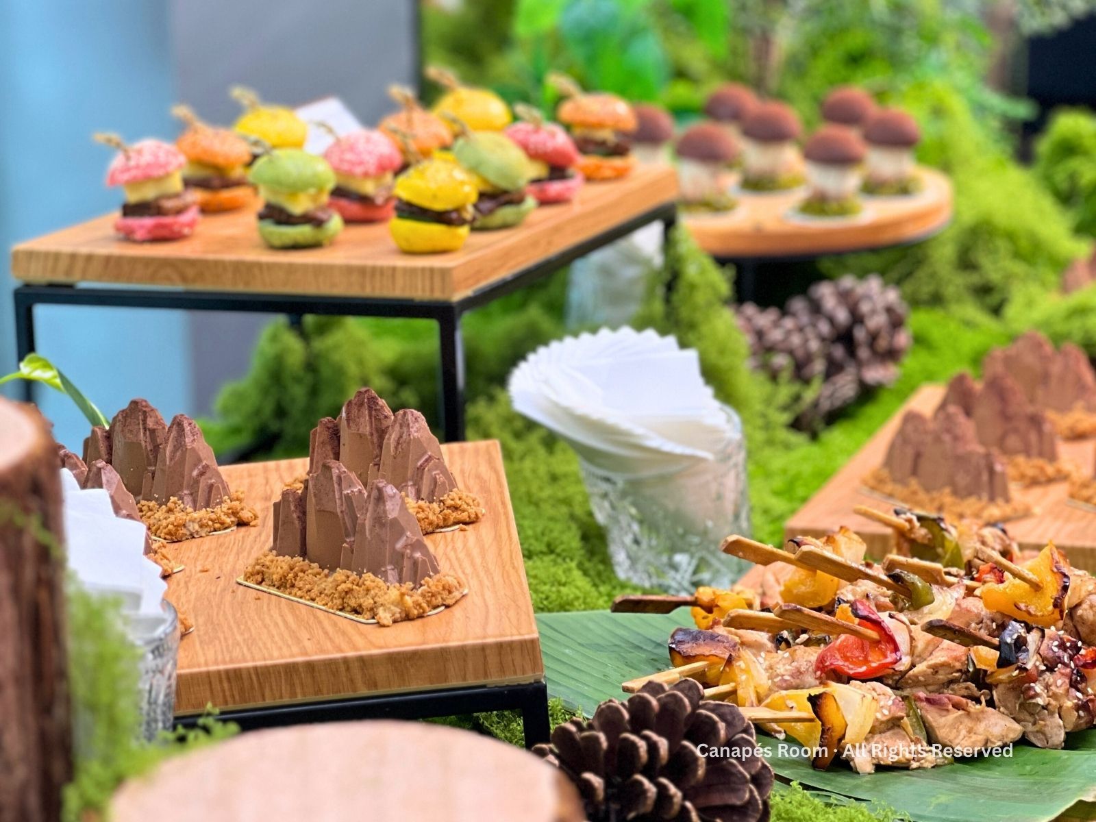 微型食品展示,苔蘚上擺放著色彩繽紛的馬卡龍、烤肉串和巧克力山。