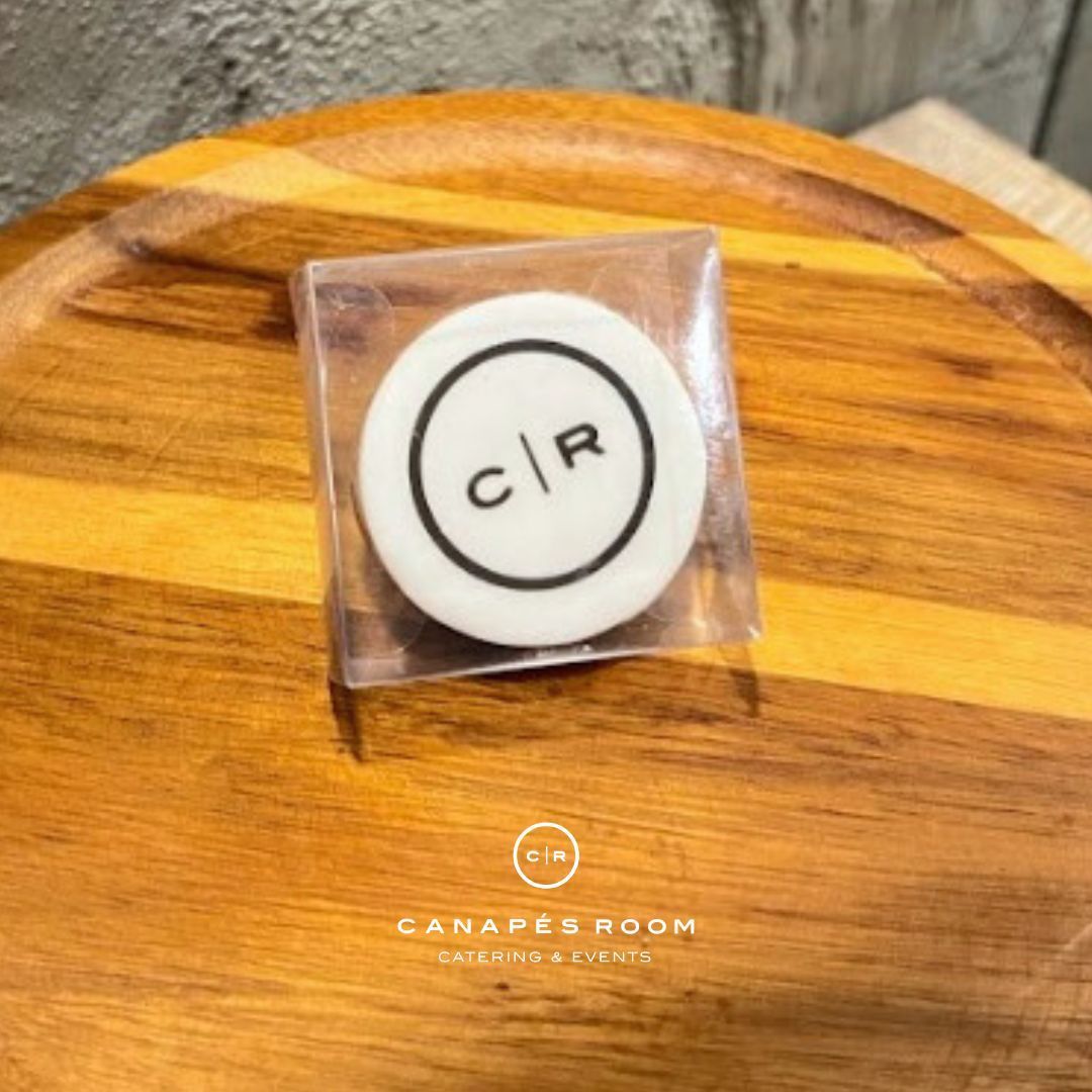 白色杯墊，圓圈內有黑色 CR 標誌，塑膠材質，放在木質托盤上。