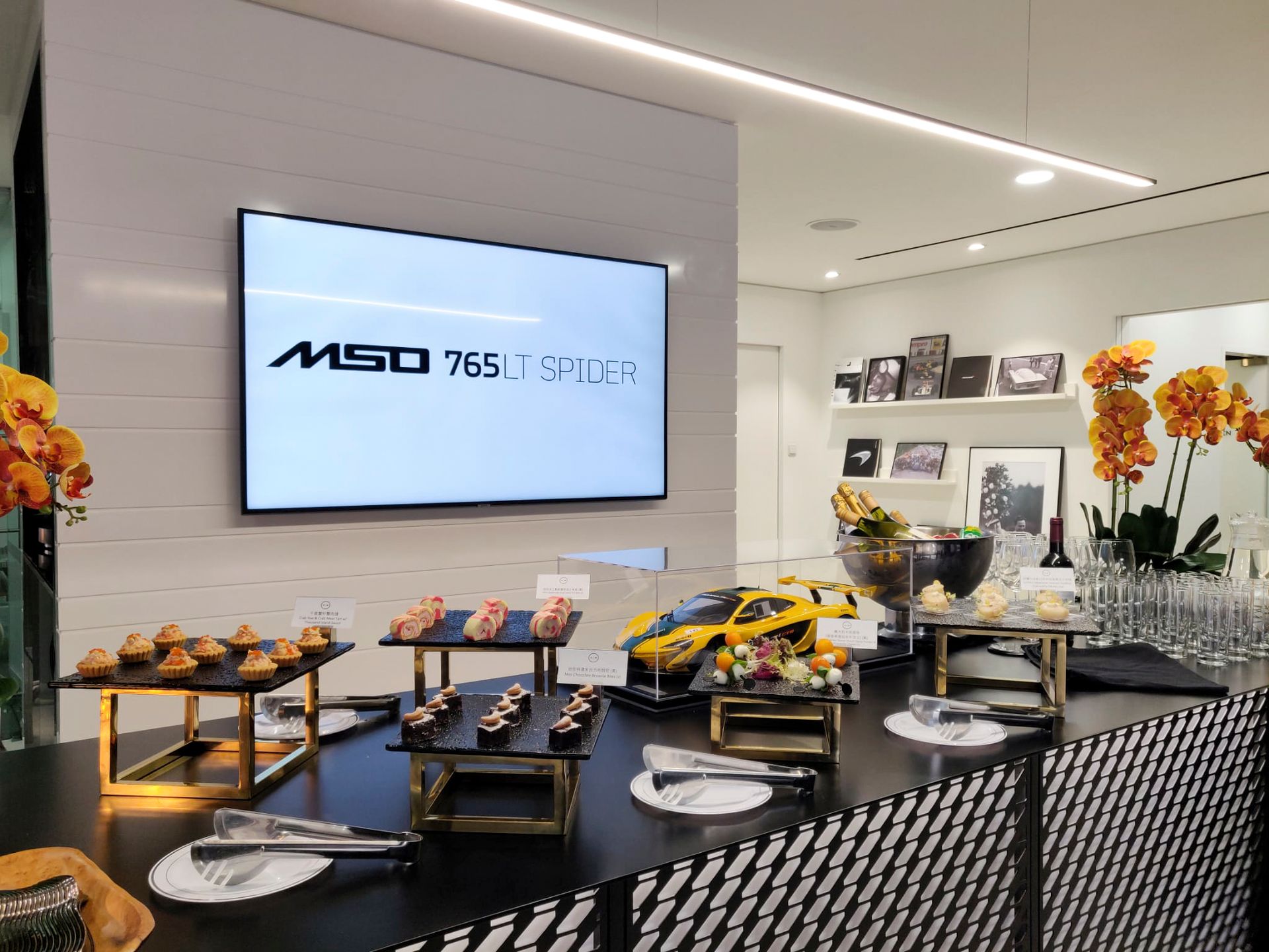 Buffet table with appetizers, small car model, and a screen that reads
