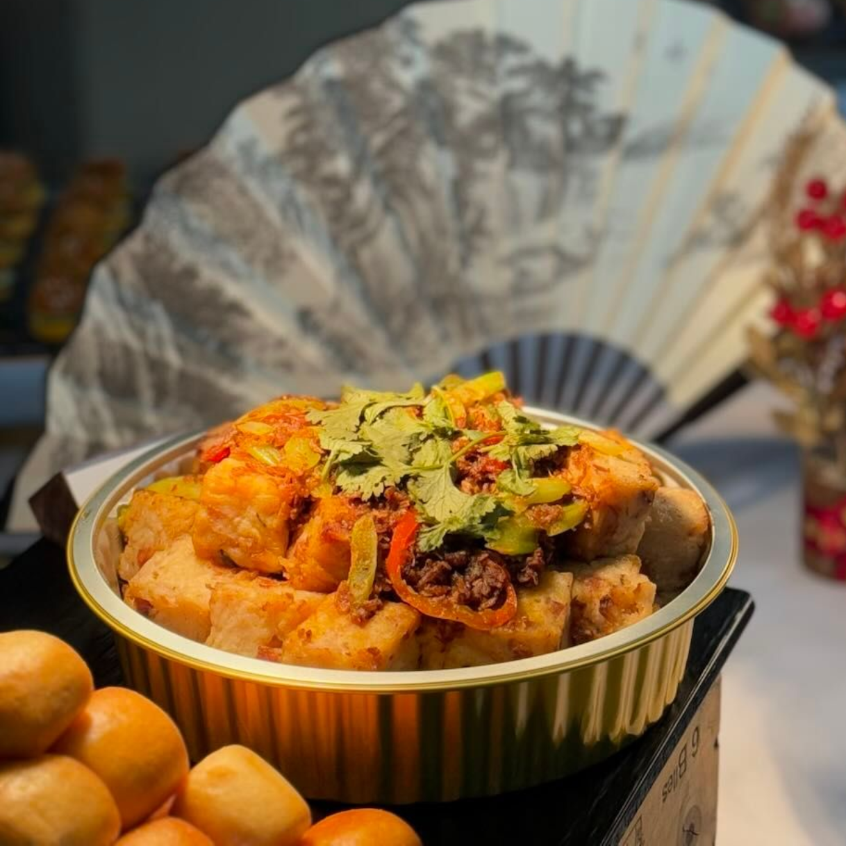 Glazed ham garnished with orange slices in a black tray, part of a buffet spread.