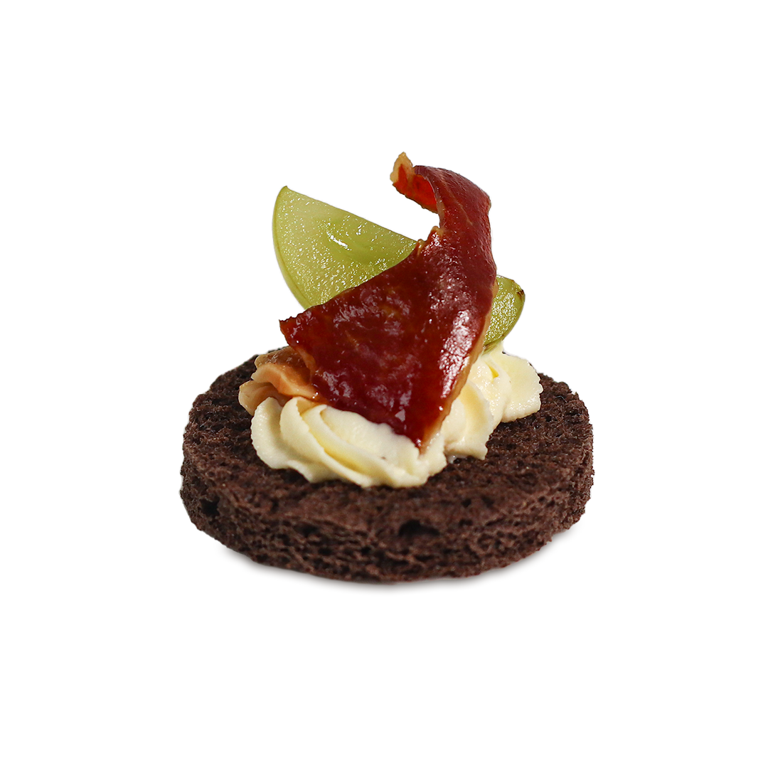 Appetizer: dark bread topped with cream, fruit, and red meat.