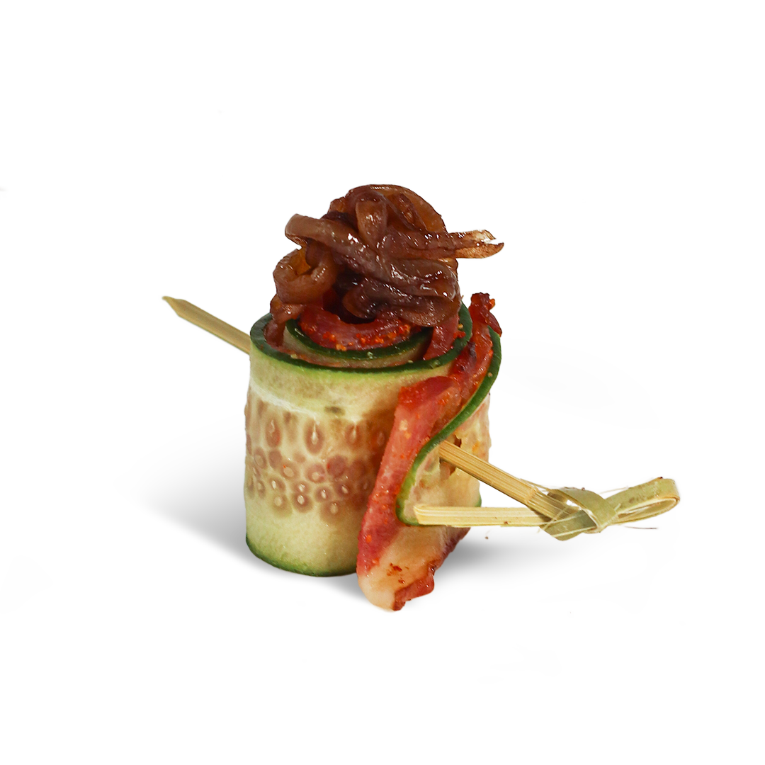 Cucumber roll appetizer with sun-dried tomato, bacon, and onion, held with a toothpick.