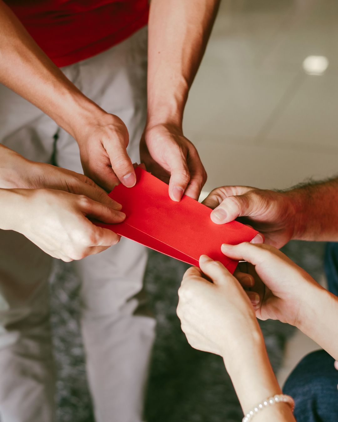 Hands holding and passing red envelopes, likely for a celebration.