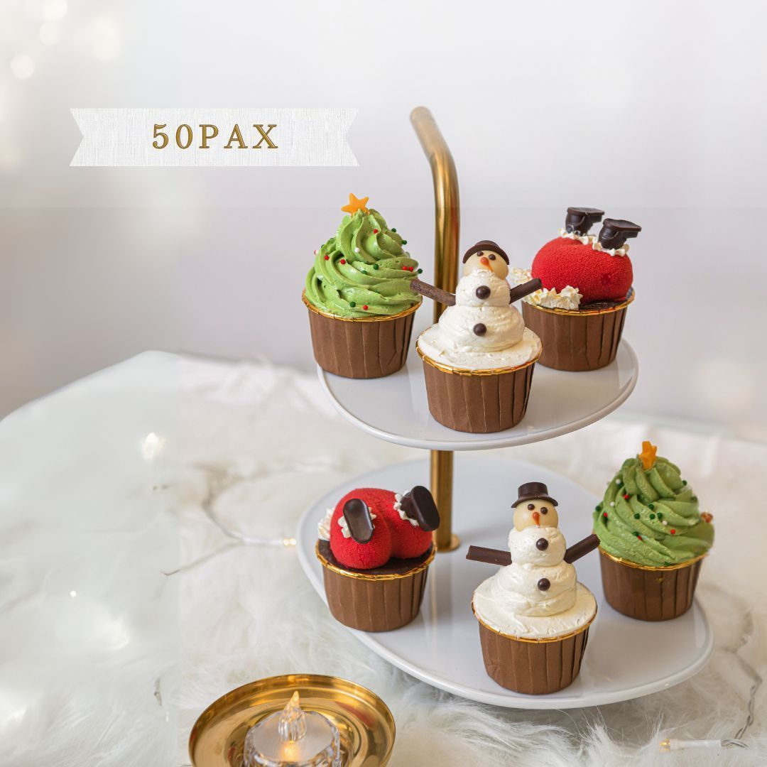 Christmas-themed cupcakes on a tiered stand. Frosting in green and white, with Santa and snowman decorations.