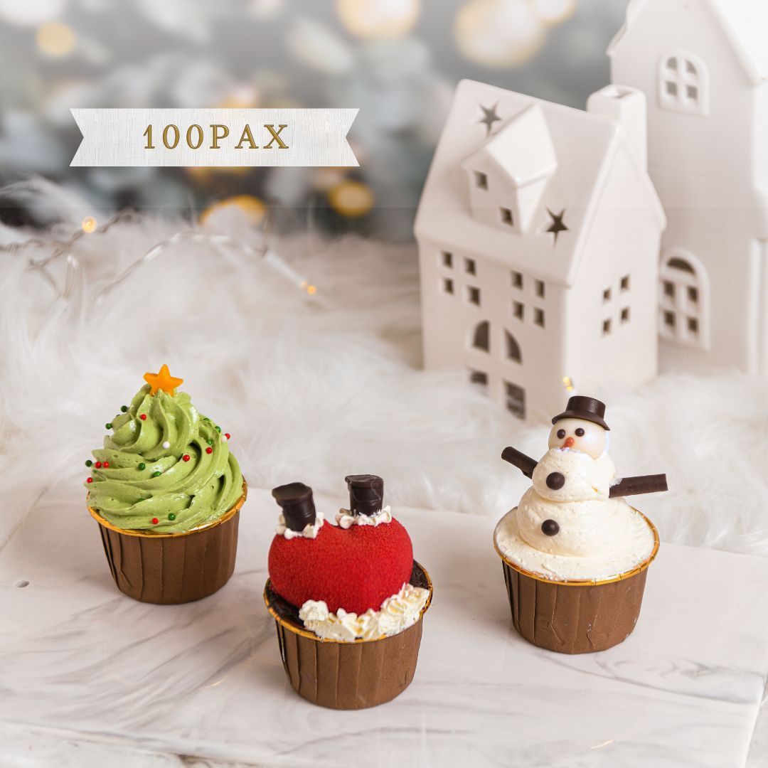 Christmas-themed cupcakes: tree, Santa, snowman. Brown cups, white frosting, star sprinkles, snowy setting, and white houses.