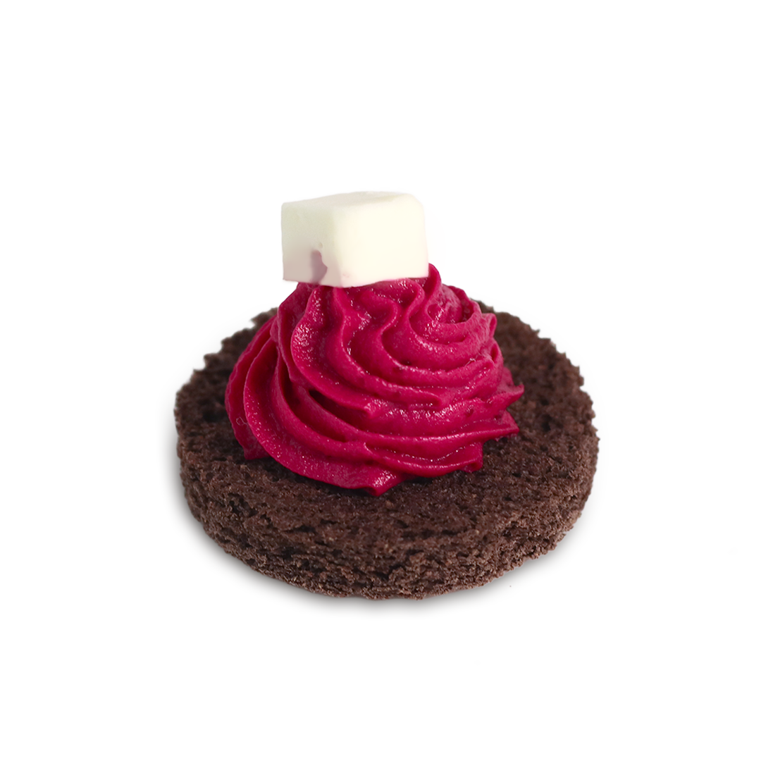 Chocolate cookie topped with bright pink frosting and white square candy.