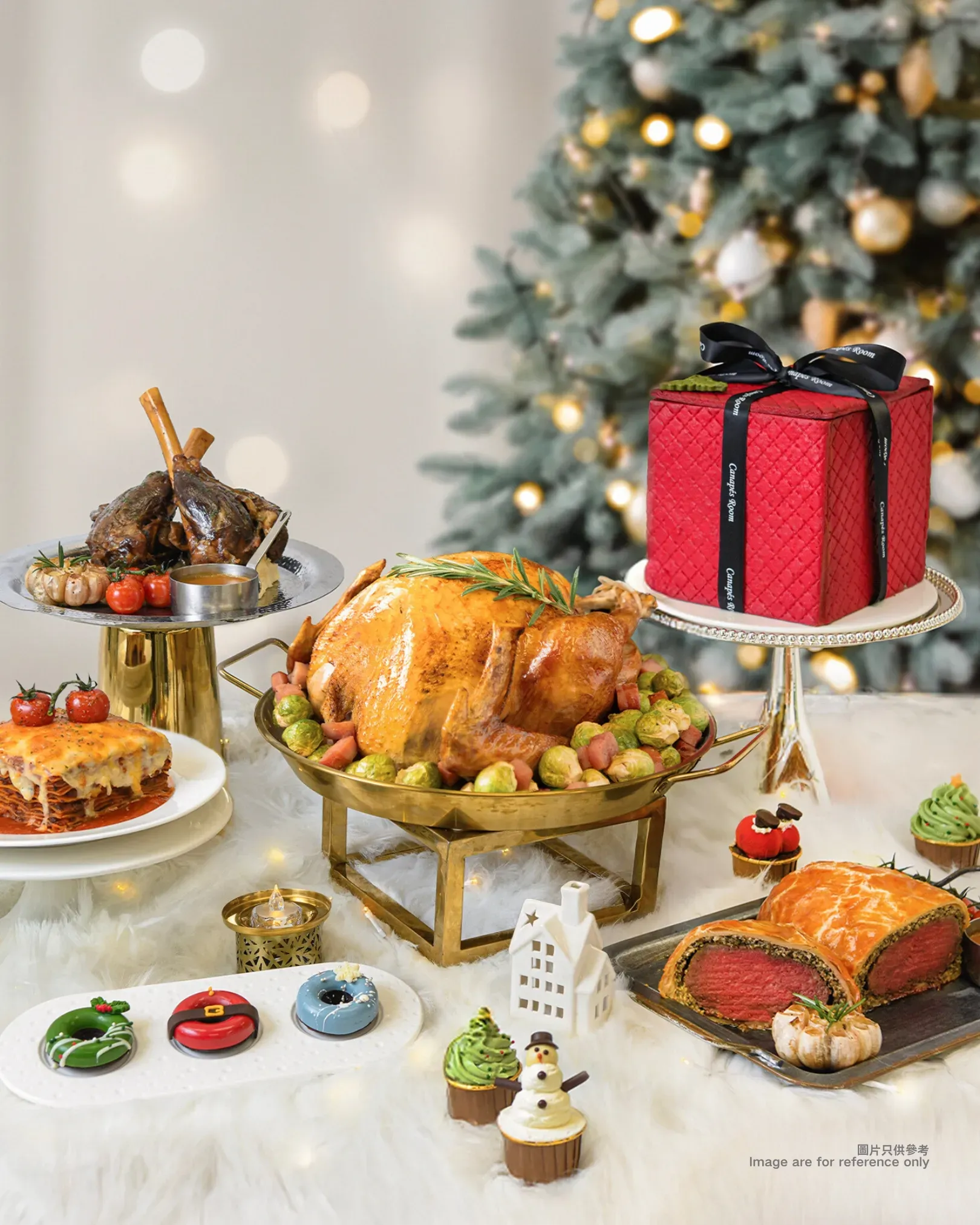 Christmas spread: roasted turkey, lamb shank, cakes, and desserts on a table with a tree and lights.