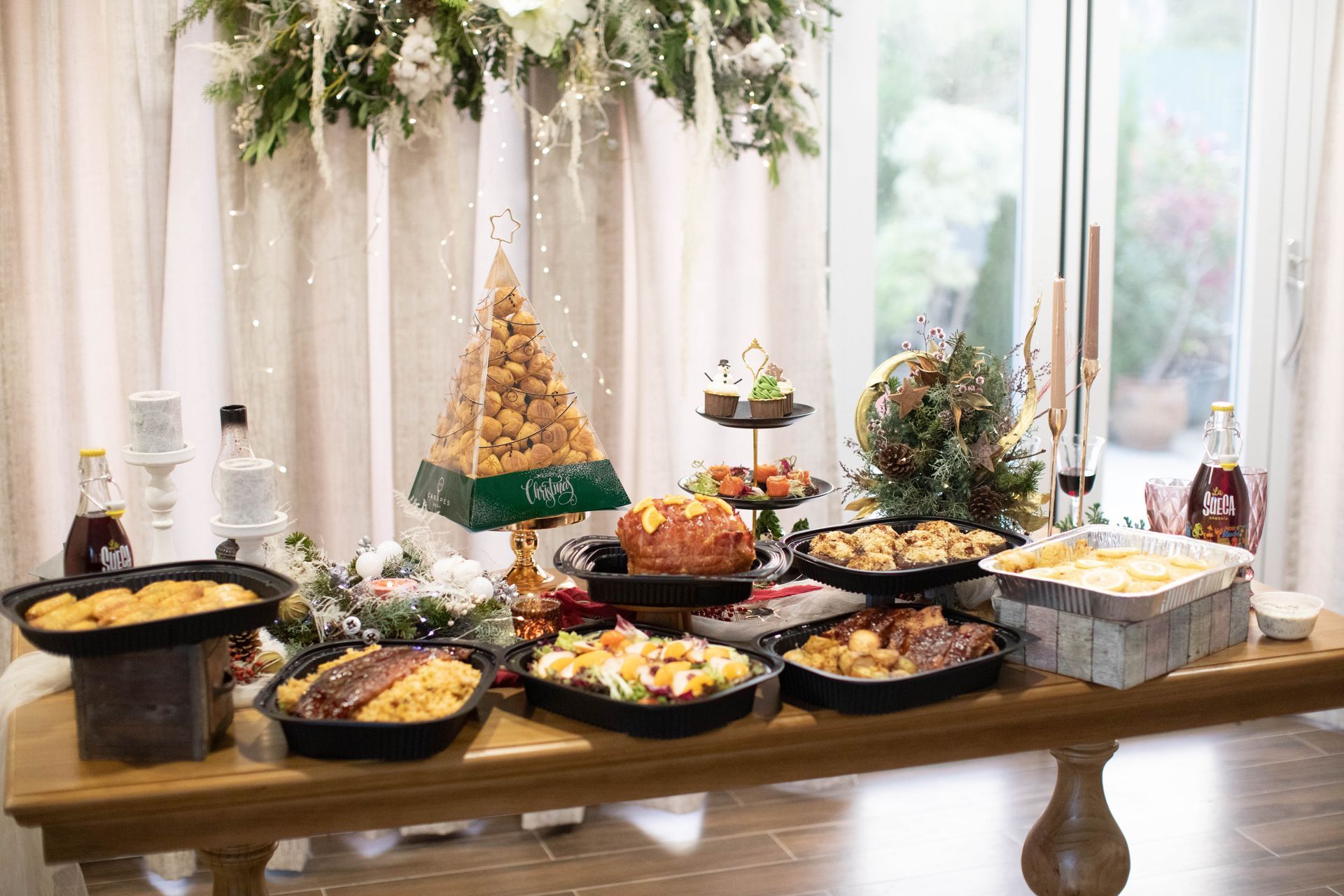 A buffet table with various dishes and decorations, set in front of a window.