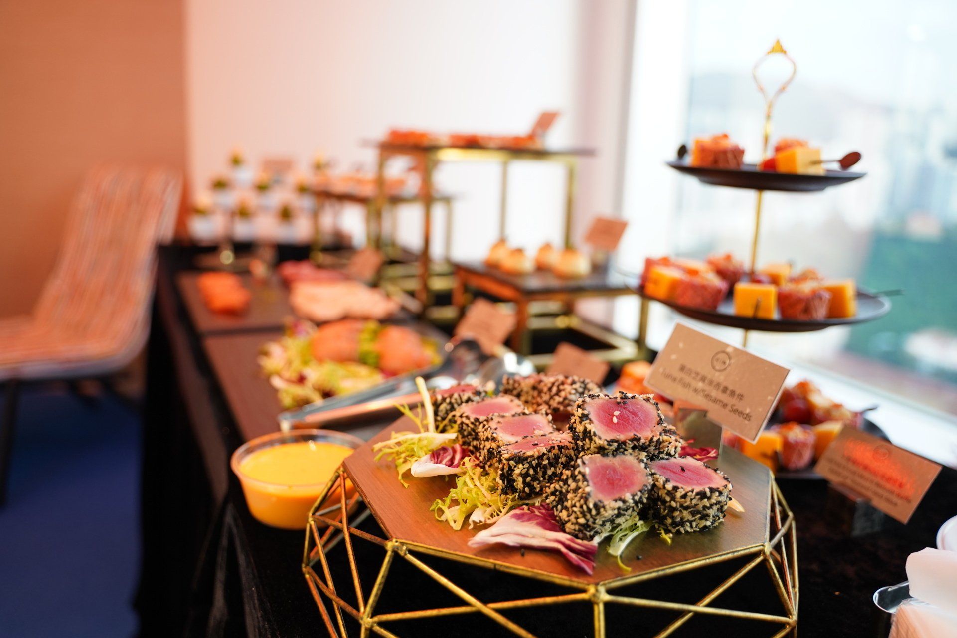 Buffet table with various appetizers, including tuna bites and salmon, arranged on tiered platters.