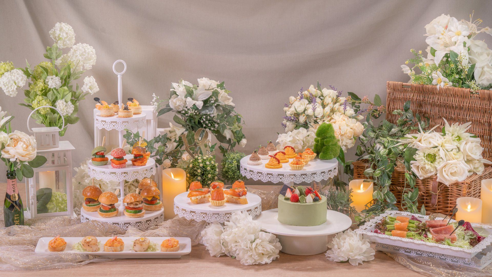 A dessert buffet with pastries and salads, decorated with white flowers and candles.