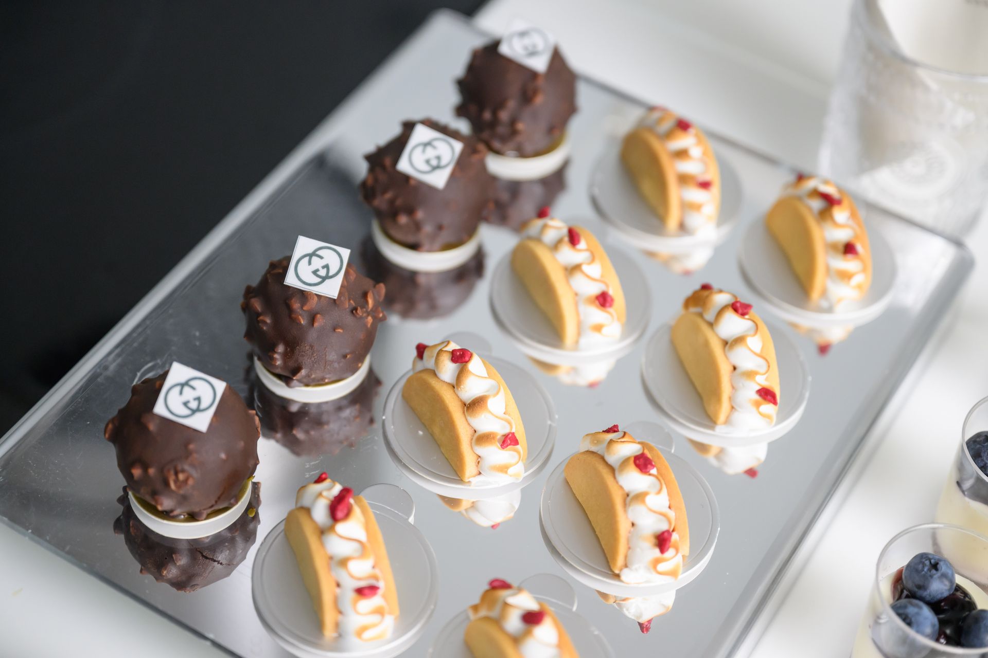 Tray of chocolate desserts and miniature taco-shaped pastries, with a logo on some.